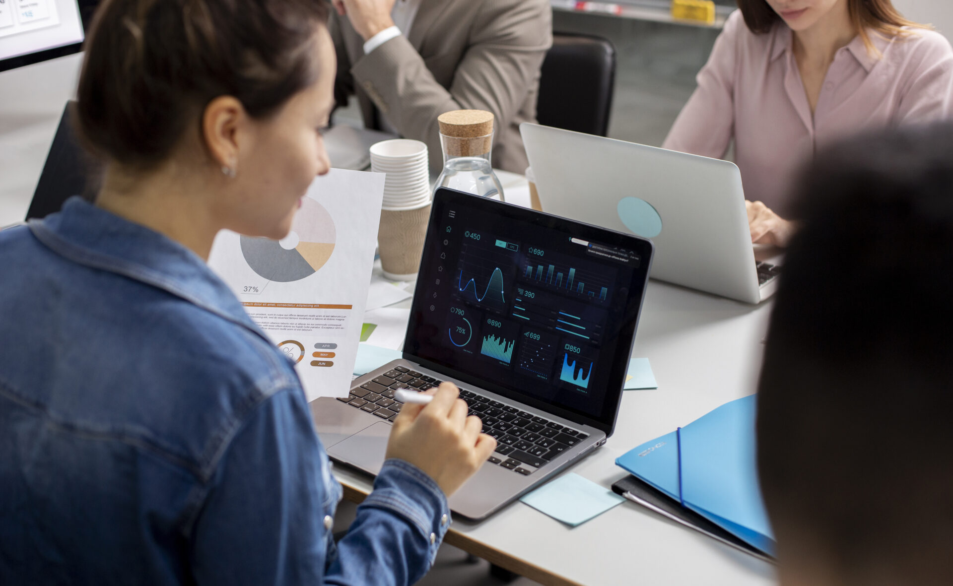 Professionals analyzing data charts on laptops during a strategy meeting for Digital Transformation Consulting by Kautilyam.